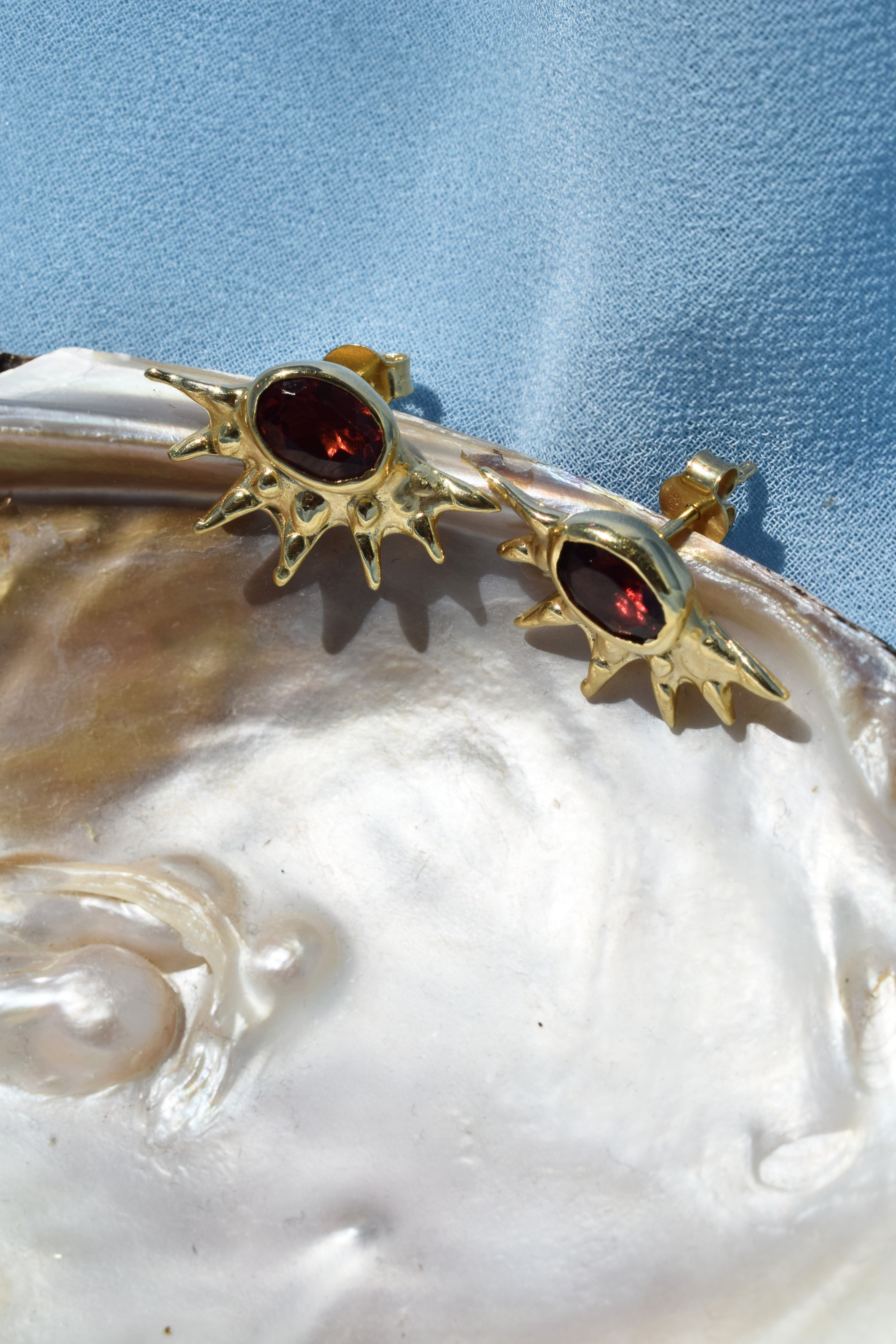 Sunburst stud earrings with red garnets
