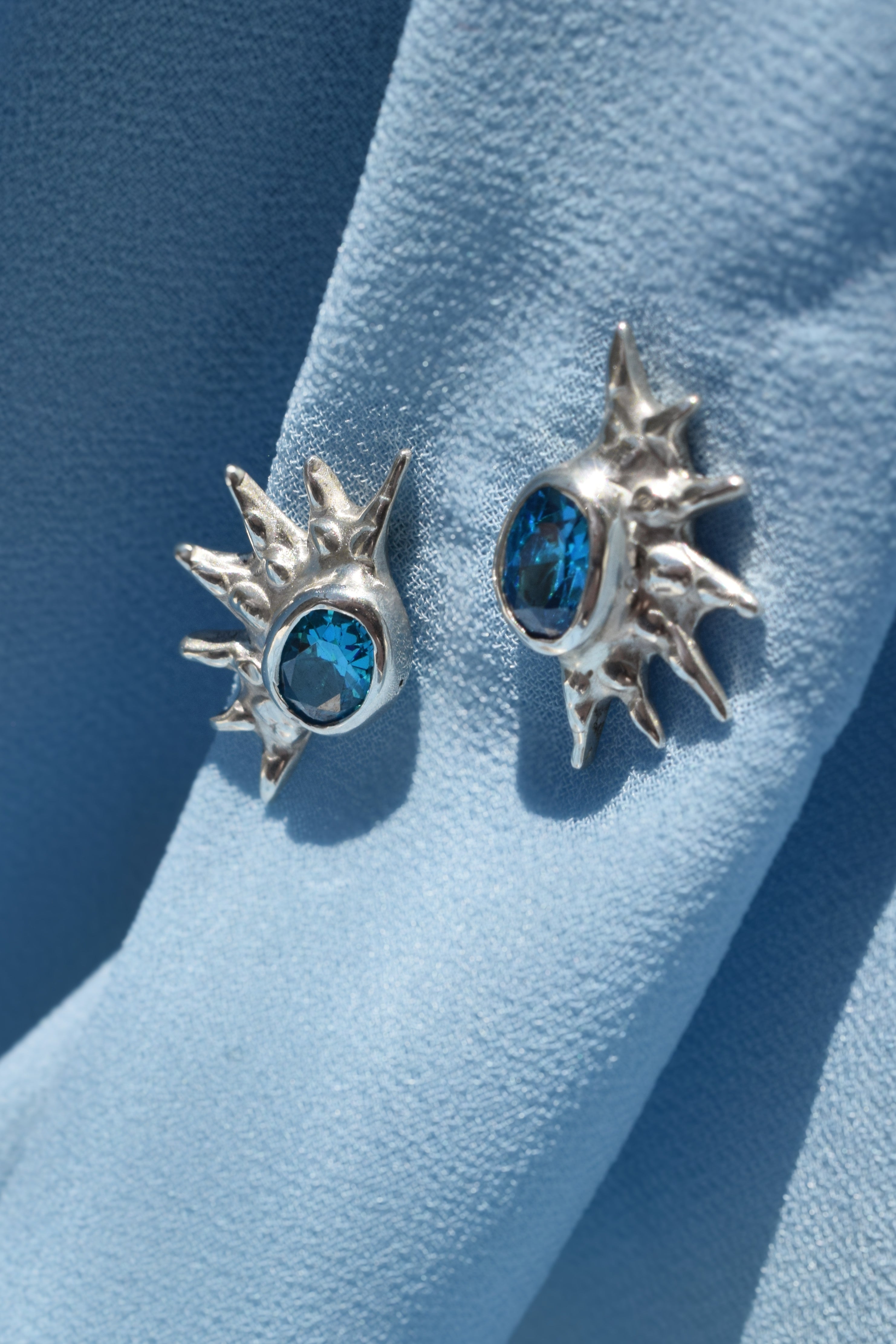 Sterling silver sunburst stud earrings with blue cz crystals