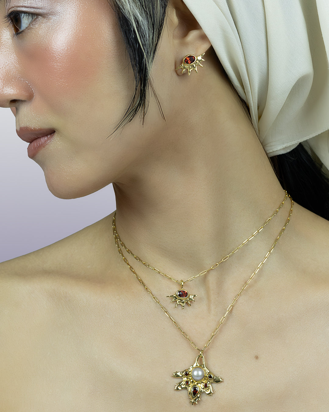 A radiant pendant on a paperclip chain, featuring a deep red garnet at the center of an asymmetrical, spiked gold setting. Bold and edgier than a traditional sunburst, it's easy to wear solo or layered.