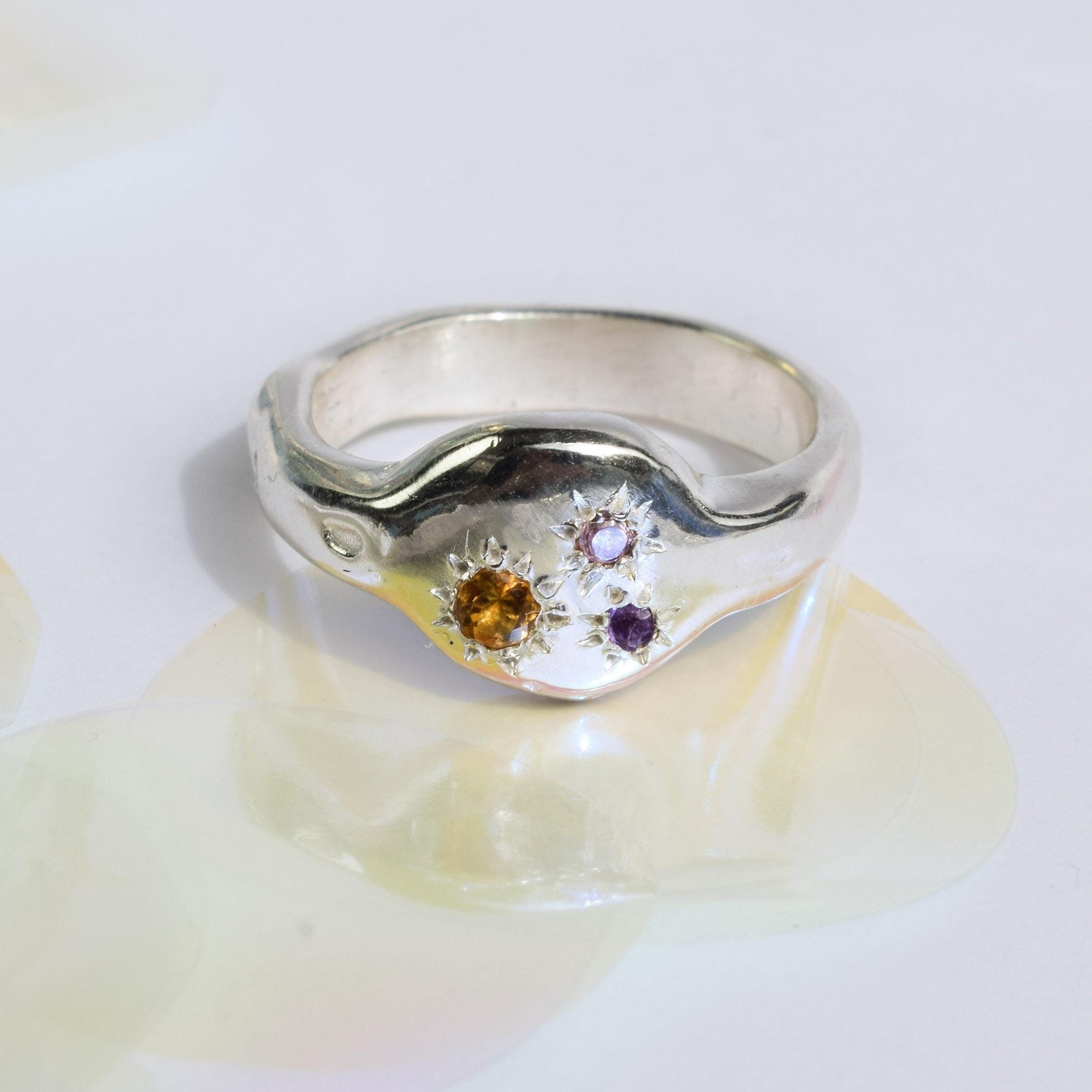 A sterling silver ring with a yellow citrine, a purple amethyst, and a pink zirconia set in an organic, minimalist design.