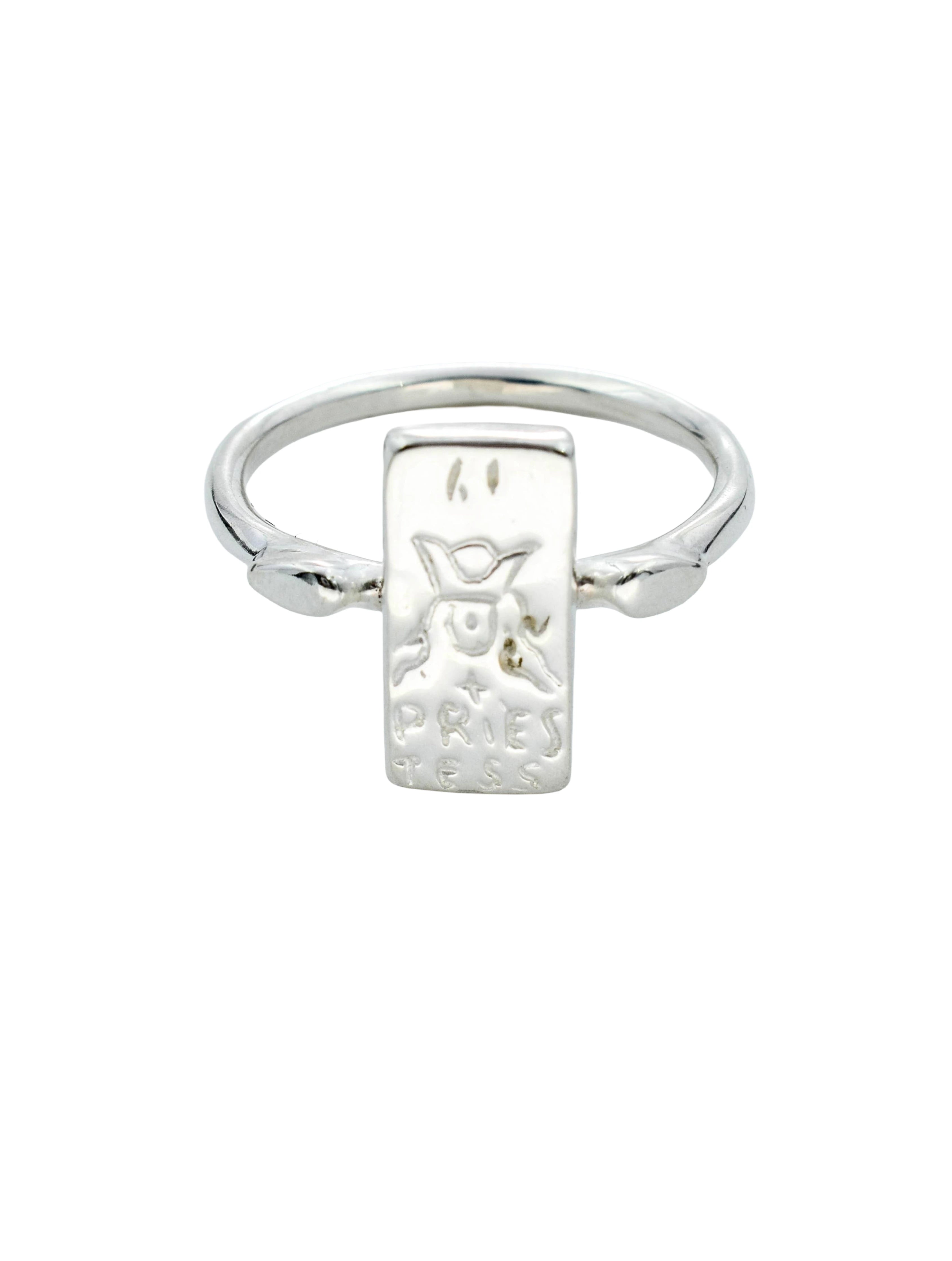 A silver ring featuring a rectangular engraved plaque with a stylized face and the text 'PRINCE', set against a plain white background.