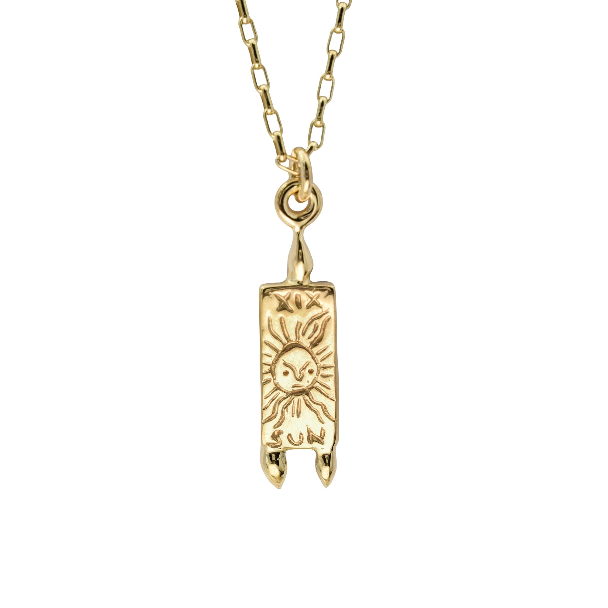 A gold pendant necklace featuring a vertical rectangular tag-style charm with an engraved sun and rabbit motif, suspended from a gold chain on a plain white background.