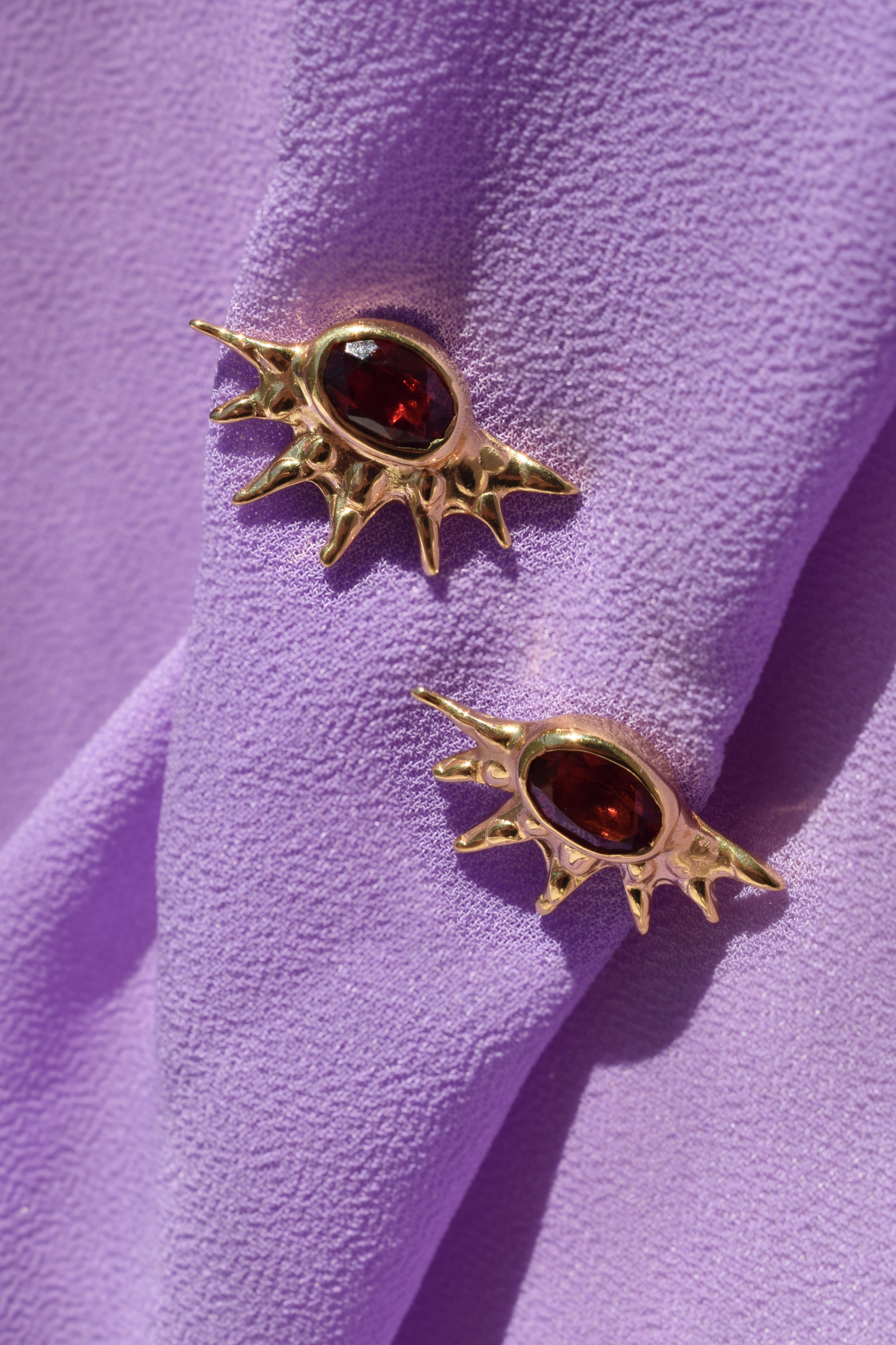 Sunburst stud earrings with red garnets