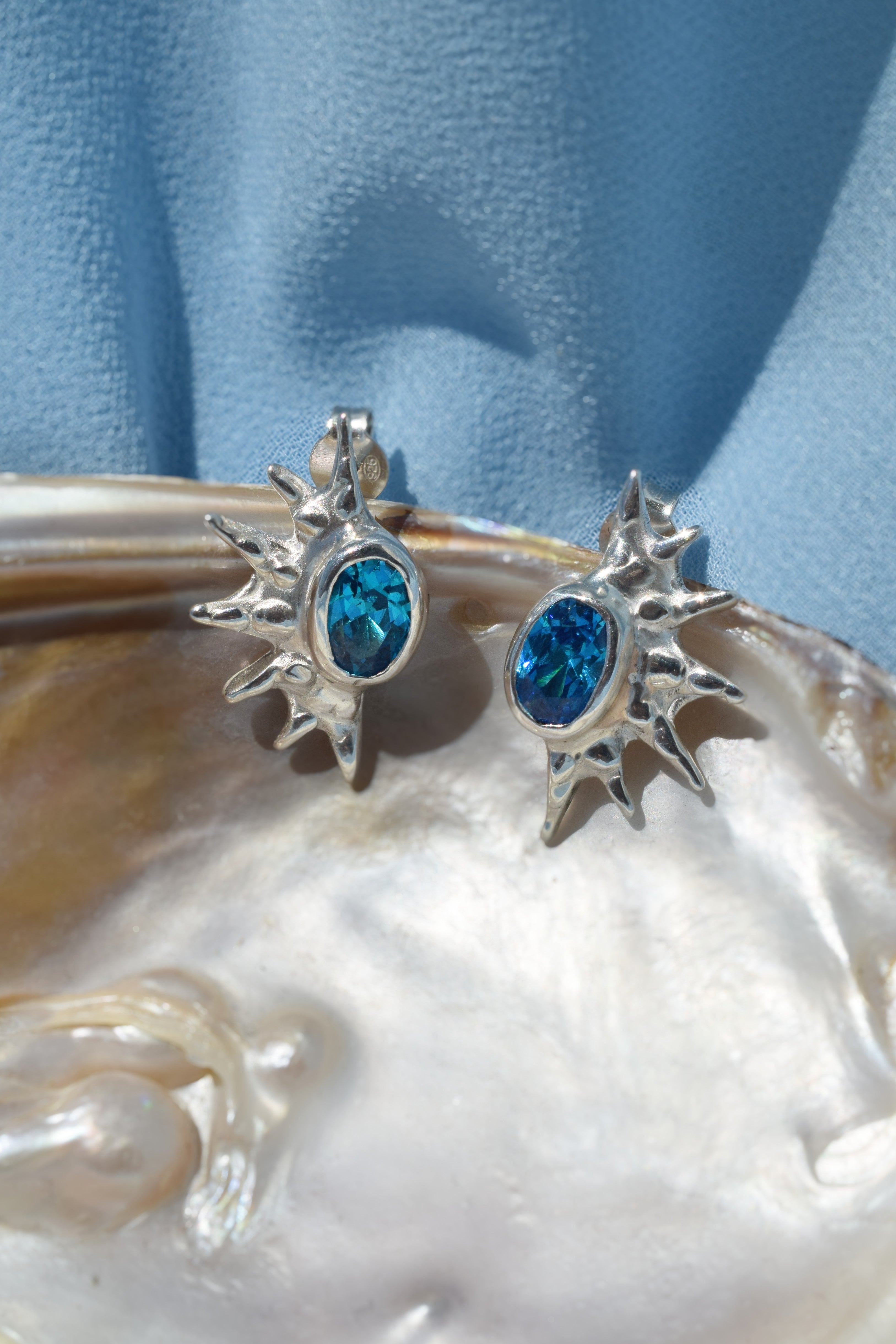 Sterling silver sunburst stud earrings with blue cz crystals