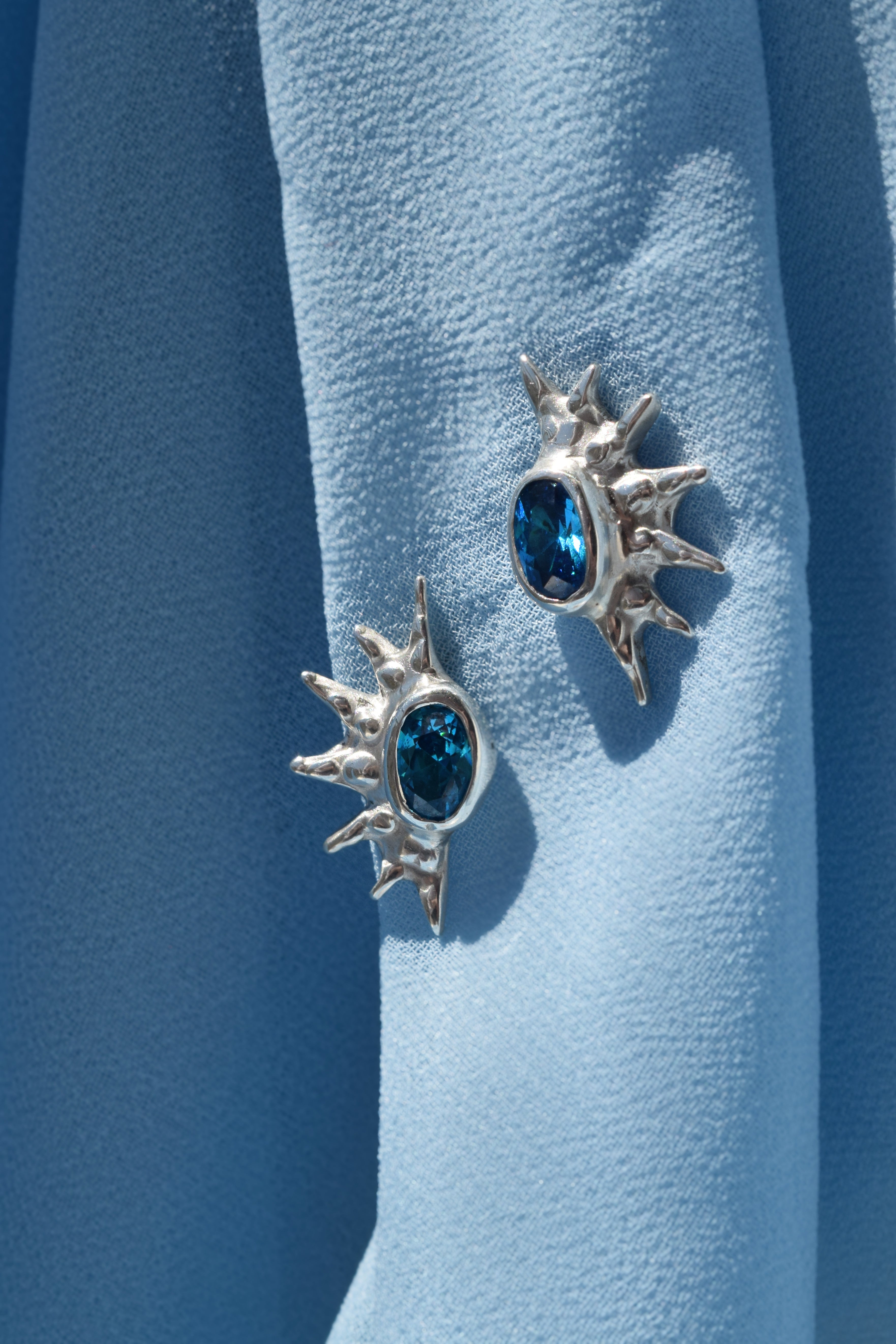 Sterling silver sunburst stud earrings with blue cz crystals