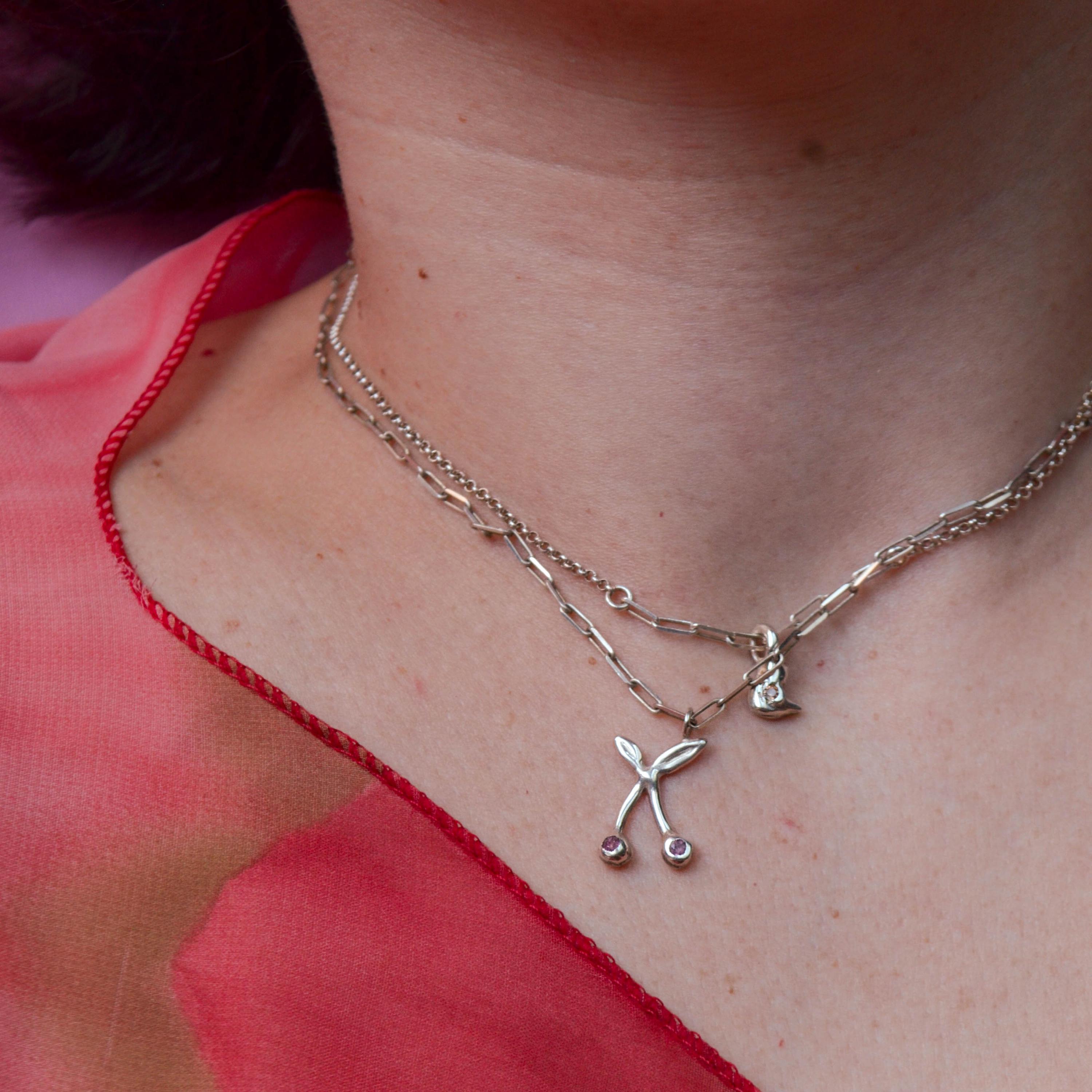 Close-up of a person wearing a delicate necklace with small pendants against a blurred background.