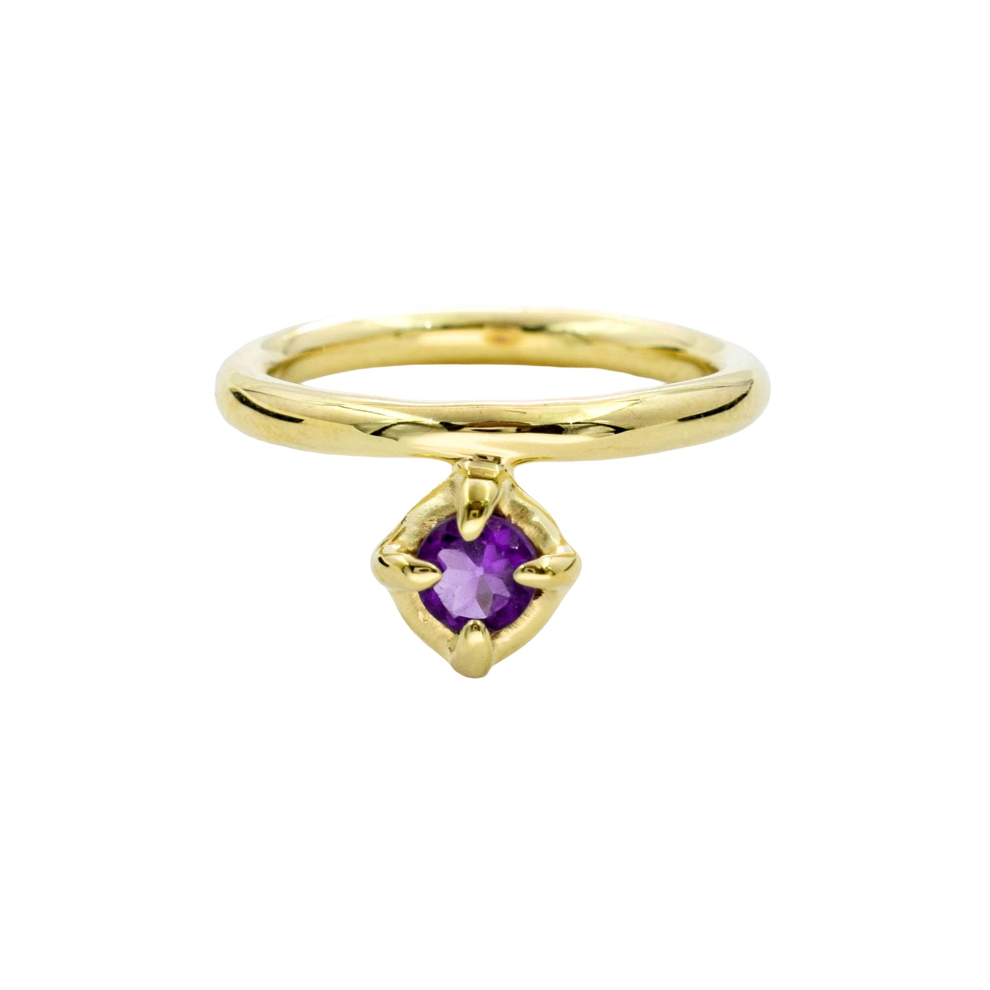 A gold ring featuring a small, bezel-set purple gemstone in a four-prong setting, shown against a plain white background.