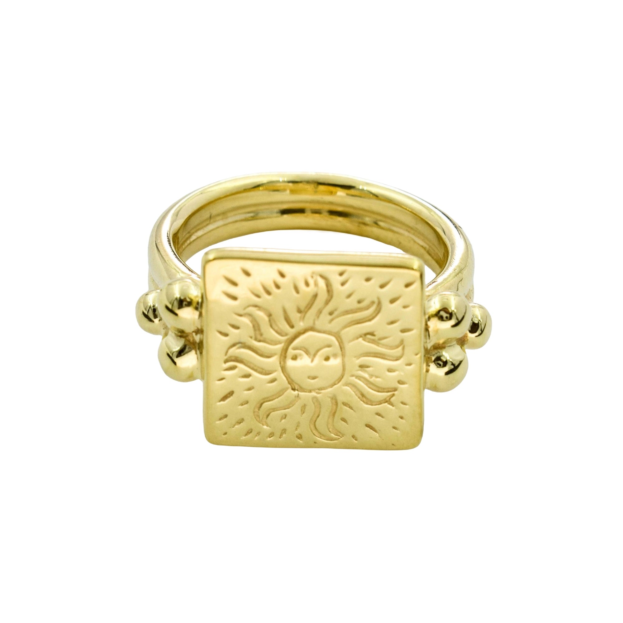 A gold signet ring featuring a square face with an engraved sun design, flanked by small bead clusters on a plain white background.