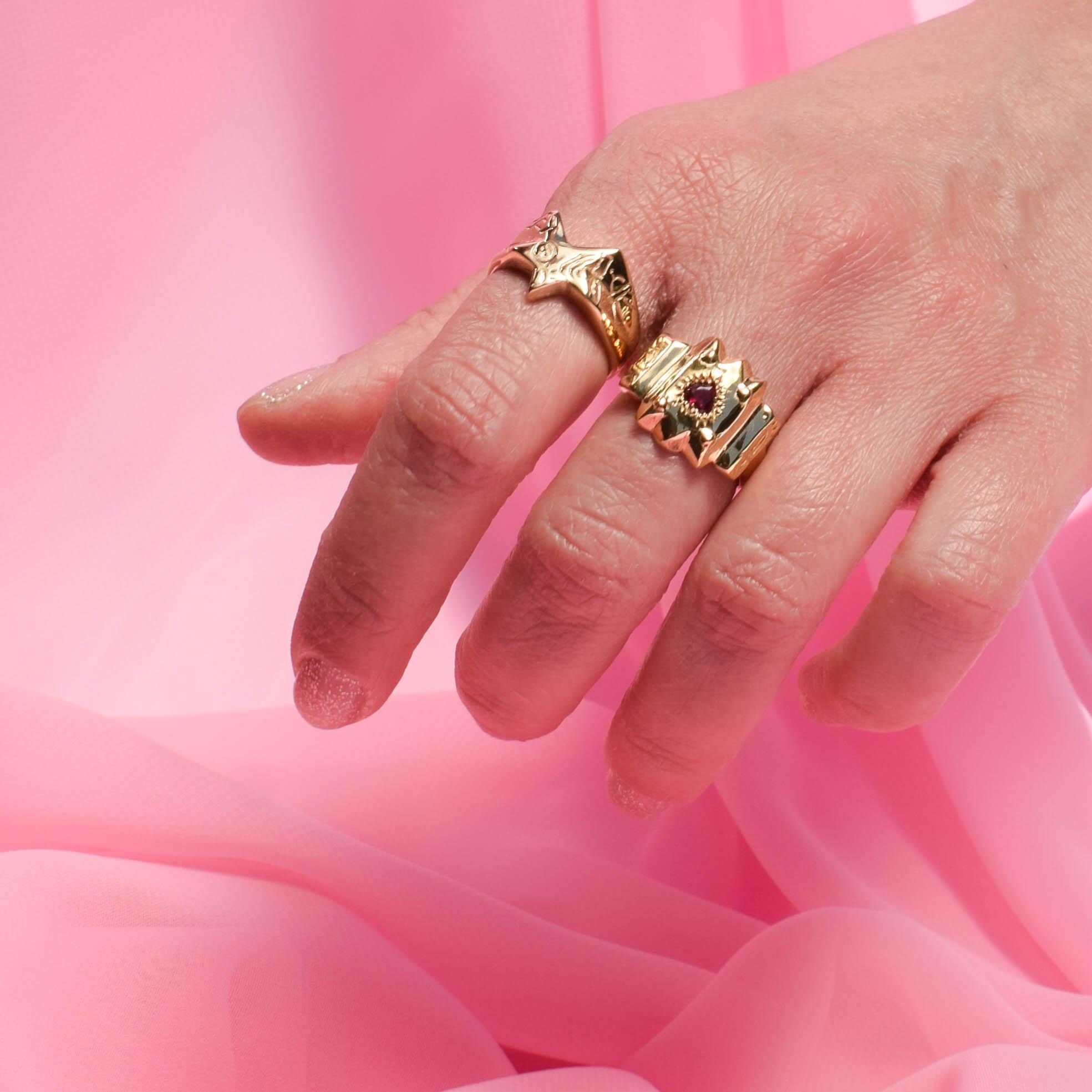 Gold rings on a hand with a pink background
