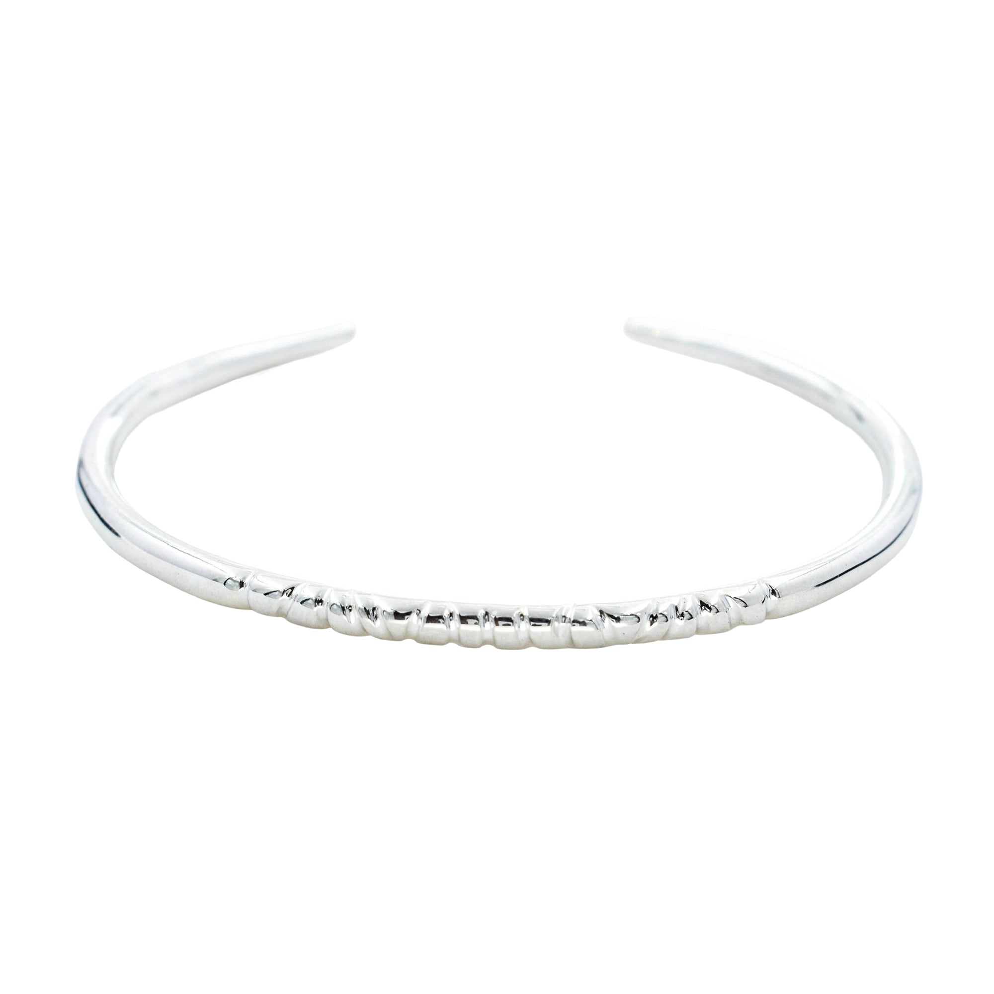 A polished silver open cuff bangle bracelet with a textured beaded segment along the front curve, shown on a plain white background.